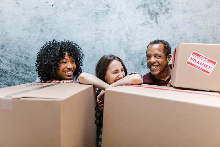 pexels-photo-7464473 - EZ Movers | New Orleans Moving Company Three friends leaning on large cardboard boxes during a move, with one box labeled Fragile.